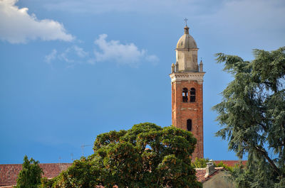 Low angle view of trees and building against sky