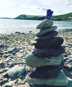 Stack of pebbles on beach against sky