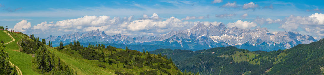 Beautiful view of alpine mountain scenery, blooming green meadows, snow-capped mountain peaks.