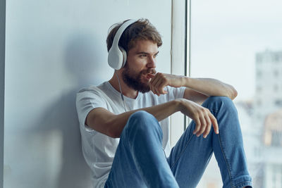 Young man sitting against wall