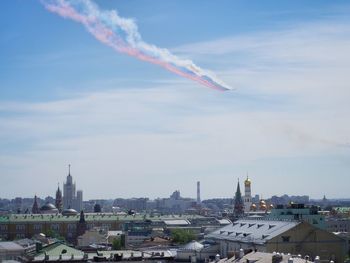 Airplane flying over cityscape against sky