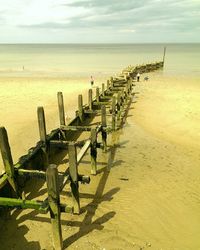 Wooden posts on beach against sky