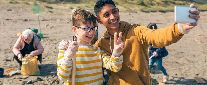 Brothers taking selfie while cleaning beach