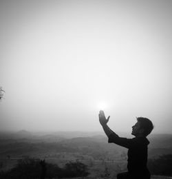 Side view of silhouette man standing on landscape against sky