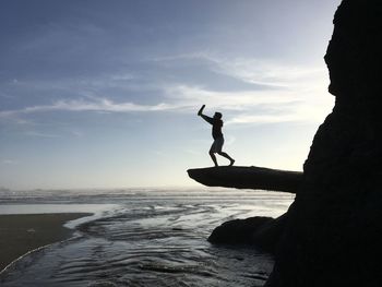 Silhouette man jumping on sea against sky