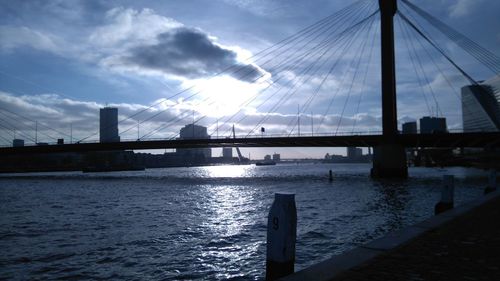 Bridge over river in city against sky