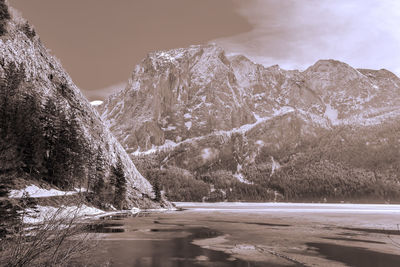 Scenic view of lake by snowcapped mountains against sky