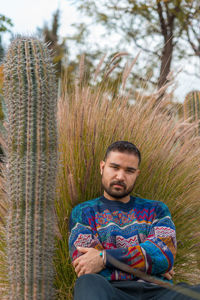 Portrait of young man sitting against trees