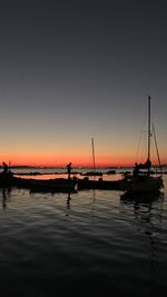 Silhouette sailboats in sea against sky during sunset