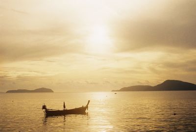 Silhouette people on boat in sea against sky during sunset