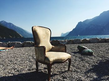 Chair by sea against clear sky