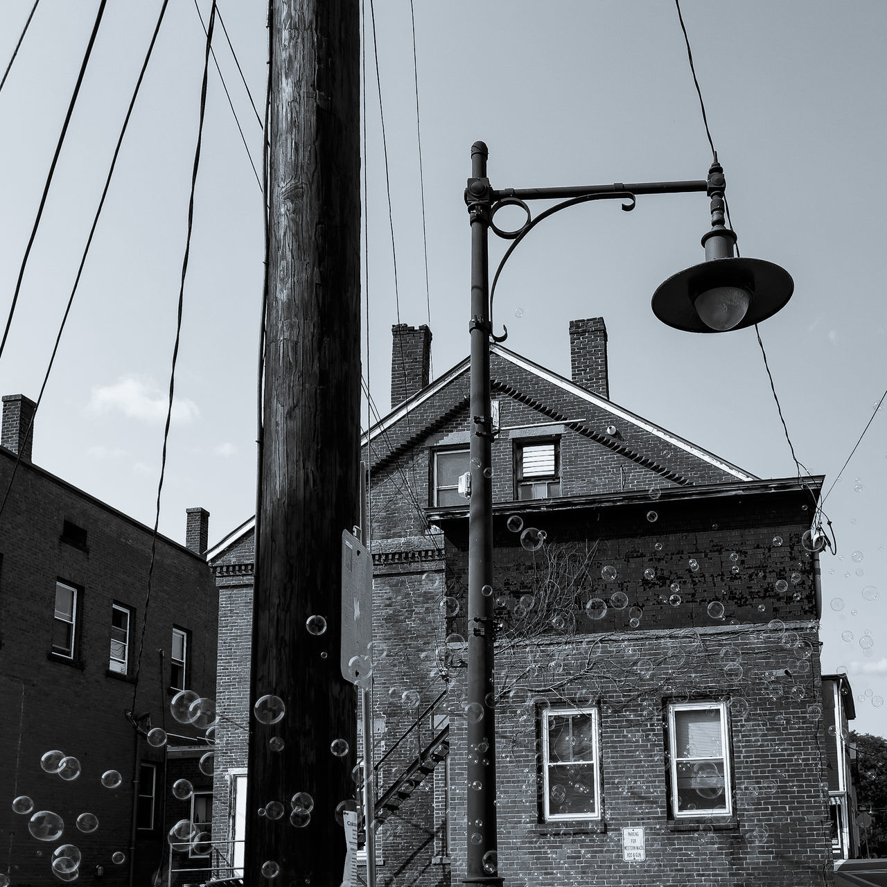 architecture, built structure, building exterior, black and white, black, sky, monochrome, monochrome photography, cable, street, urban area, white, low angle view, no people, building, street light, city, electricity, road, nature, day, clear sky, house, residential district, outdoors, lighting, communication, technology, window, sign