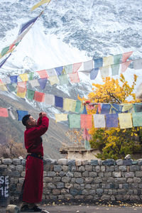 Side view of man standing by prayer flags during winter