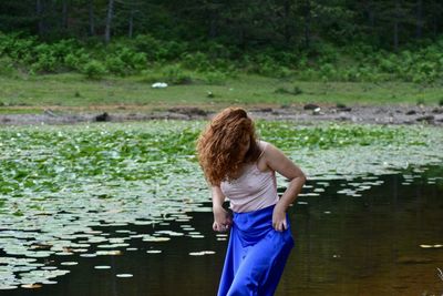 Rear view of woman standing against lake