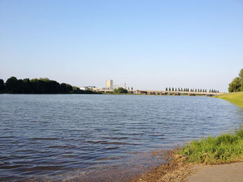 Scenic view of river by buildings against clear sky