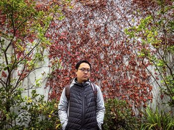 Portrait of young man standing against plants