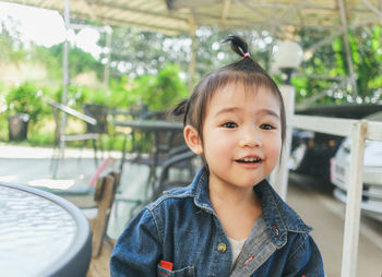 Close-up of cute baby girl sitting on chair outdoors