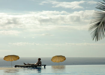 Man relaxing by sea at infinity pool