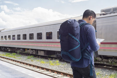 Tourist using digital tablet while standing at railroad station platform