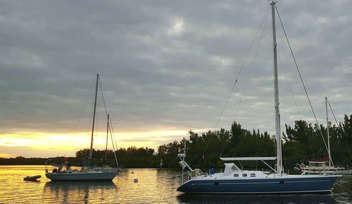 Boats in sea against cloudy sky