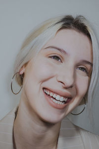 Close-up of young woman wearing blazer against wall