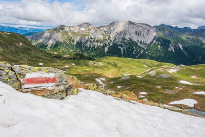 Red and white marking of the hiking trail in the austrian alps. sunny mountain panorama with snow