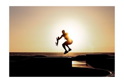 Side view of silhouette man jumping against clear sky