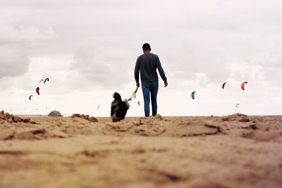 Rear view of men on beach against sky