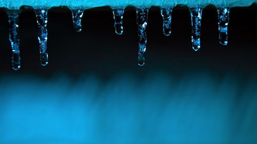 Close-up of icicles against blue sky