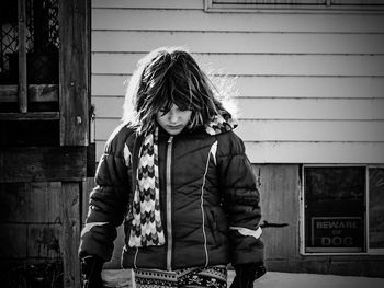 Girl wearing warm clothing walking against wooden cabin