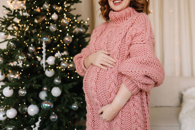 Young woman standing against christmas tree