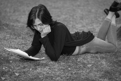 Full length of woman reading while lying down on floor