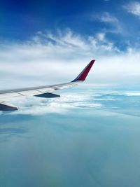 Close-up of airplane flying over sea against blue sky