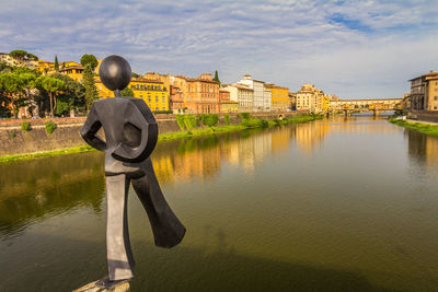 Buildings by river against sky in city