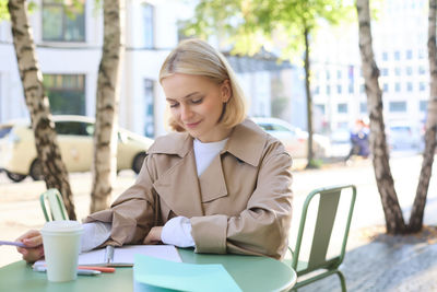 Portrait of young woman using mobile phone while sitting in cafe