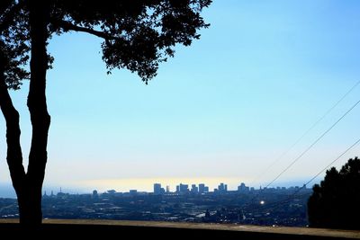 Silhouette city by sea against clear sky