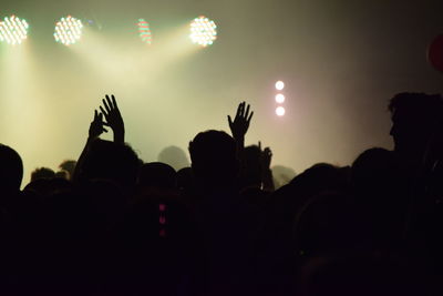 Silhouette people at music concert against sky at night