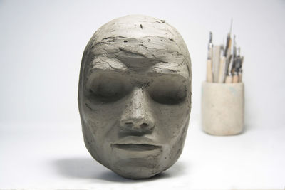 Clay face, sculpture modeling and tools on white background