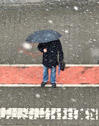 Low section of man standing on wet road during rainy season