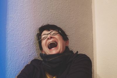 Close-up of mid adult woman laughing against wall