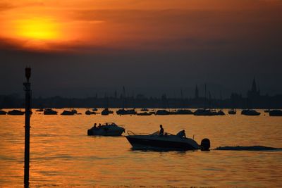 Silhouette sailboats in sea against sky during sunset