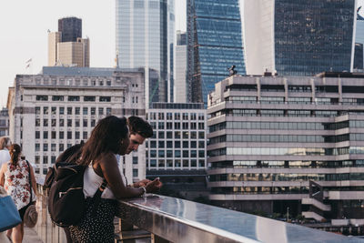 People standing by modern buildings in city