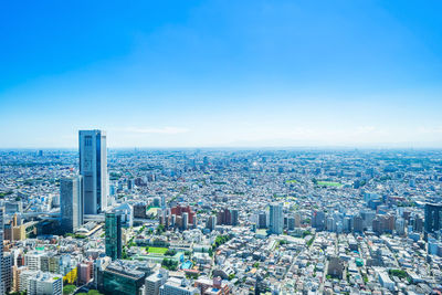 Aerial view of modern buildings in city against clear blue sky