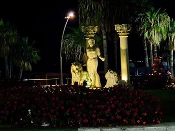 Statue by illuminated building at night