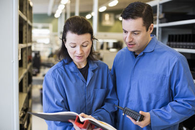 Male and female technicians discussing over documents in industry