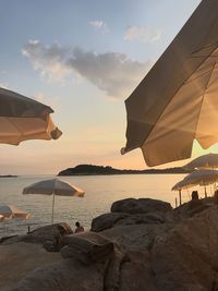 Parasols at beach against sky during sunset