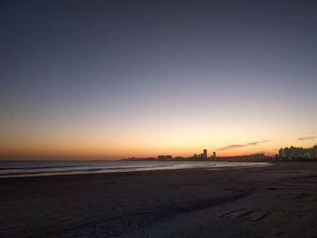 Scenic view of beach against clear sky at sunset