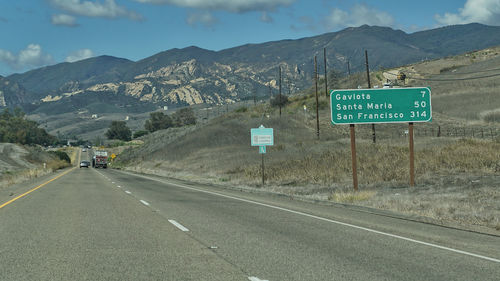 Road sign by mountains against sky