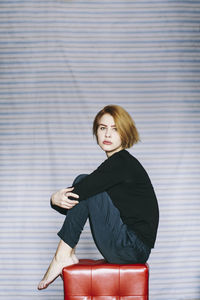 Portrait of beautiful young woman on red seat at home