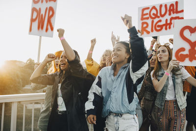 Young women shouting while protesting for equal rights against sky